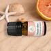 Bottle of Beach Vibes Essential Oil Blend on sandy beach with starfish, sea shells, and half of an orange, evoking summer relaxation.